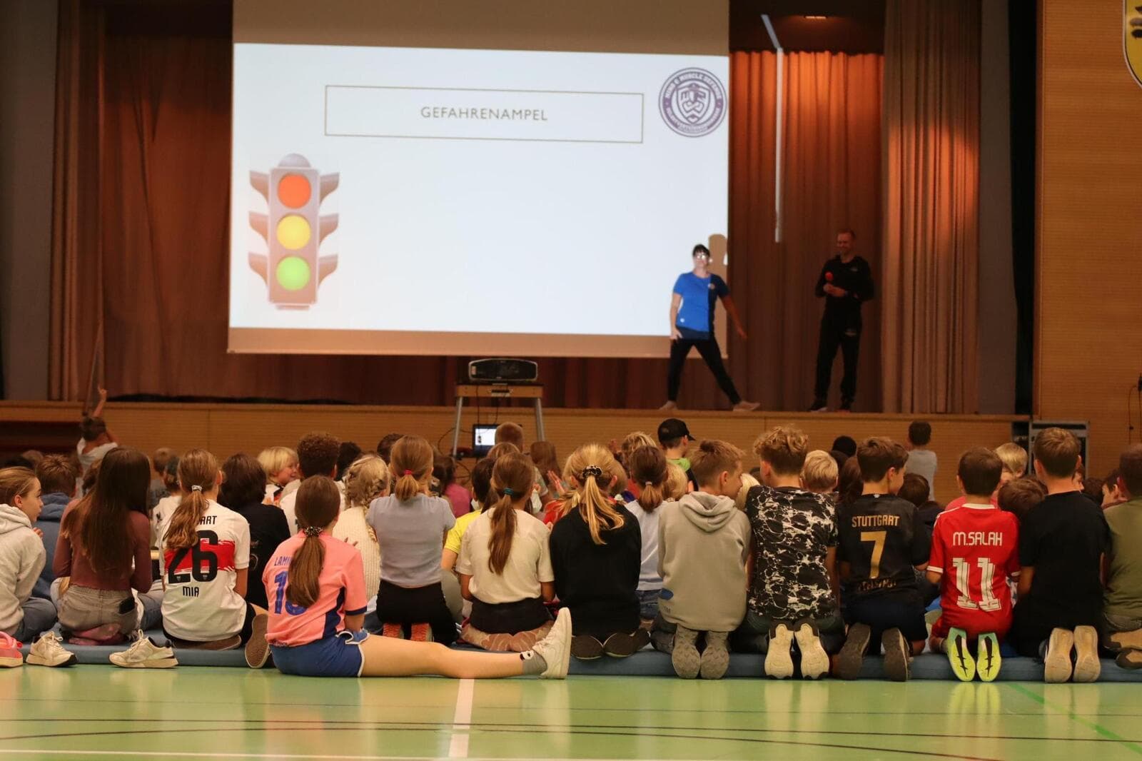 Kinder sitzen vor der Bühne, auf der Leinwand ist die Gefahrenampel zu sehen